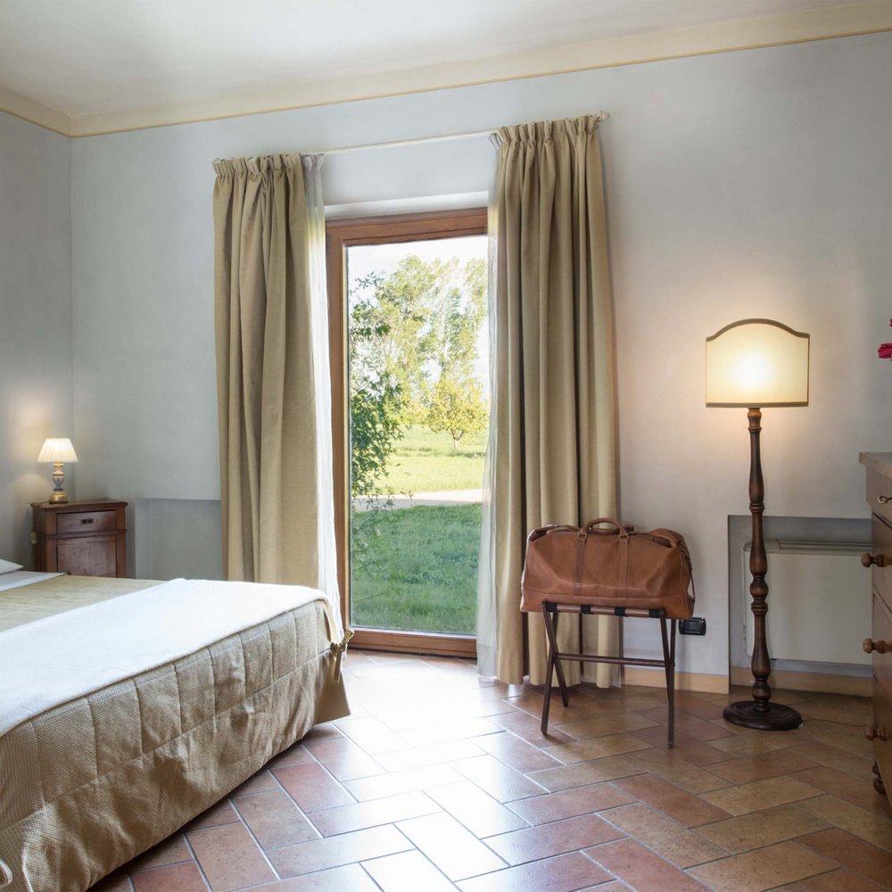 Un hotel accessibile, in Umbria, con una marcia in più Camera da letto con finestra, letto matrimoniale e arredamento classico in legno.