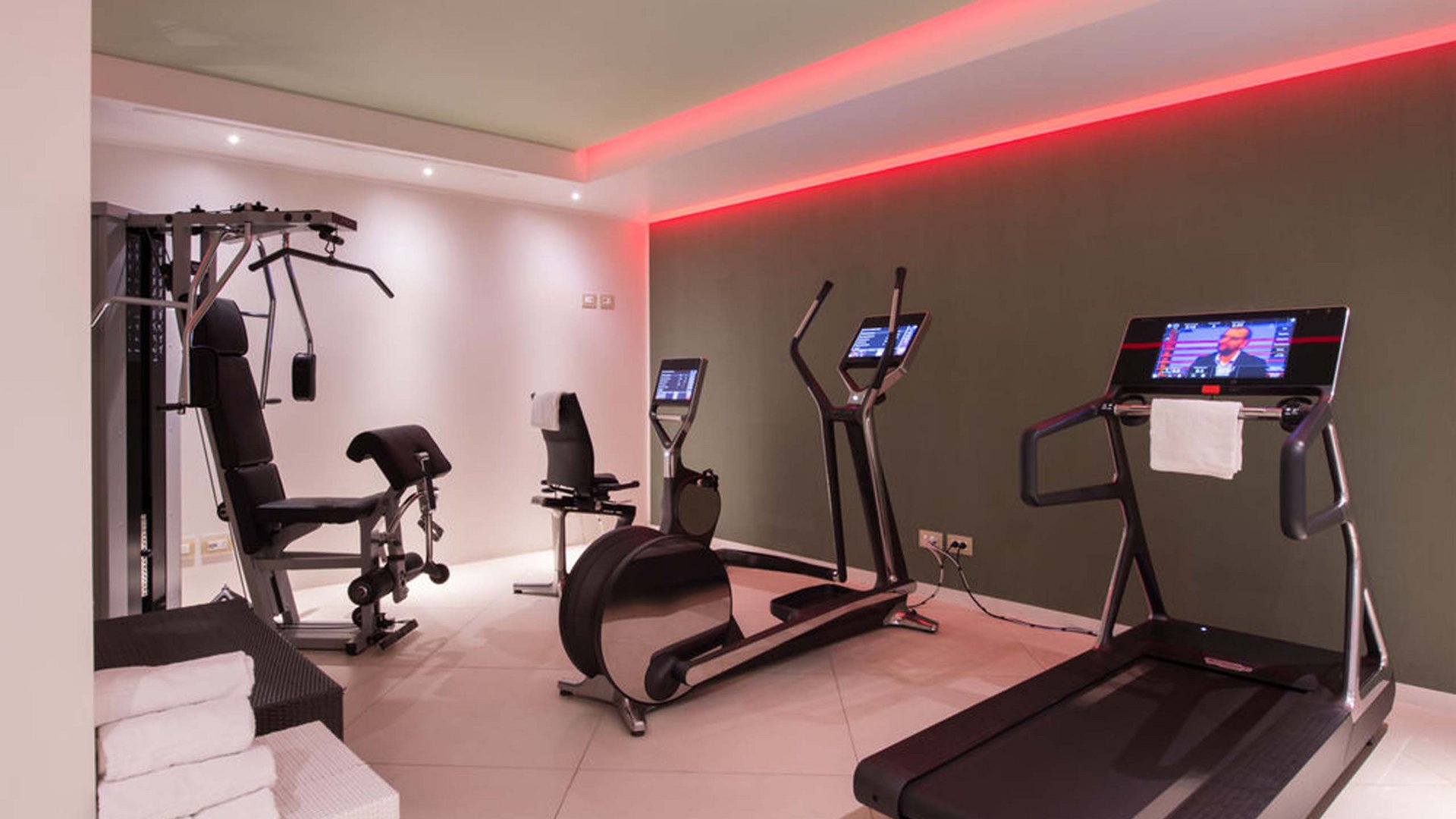 Un hotel con spa per famiglie e area fitness Palestra moderna con tapis roulant, cyclette, pesi e illuminazione LED rossa