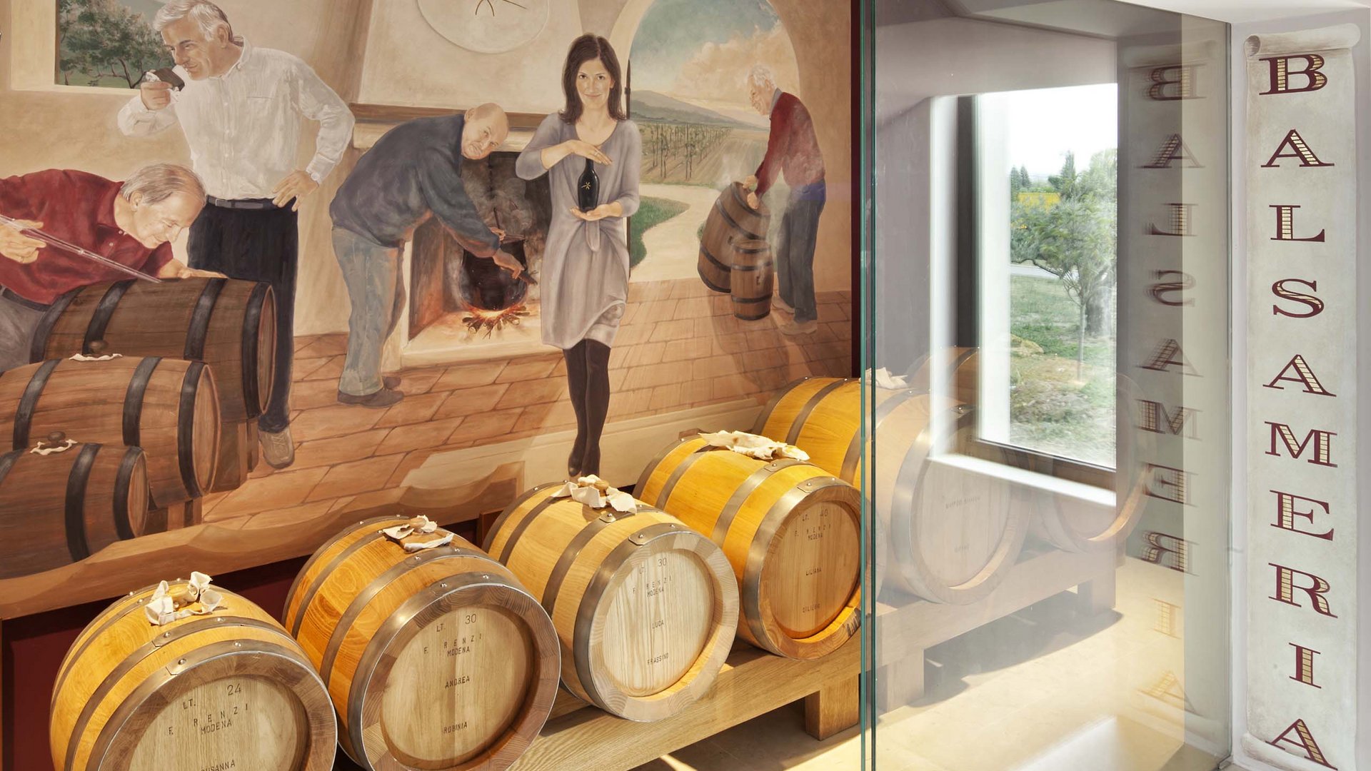 Un hotel vicino ad Assisi con mezza pensione da sogno Barili di legno per balsamico davanti a murale in cantina