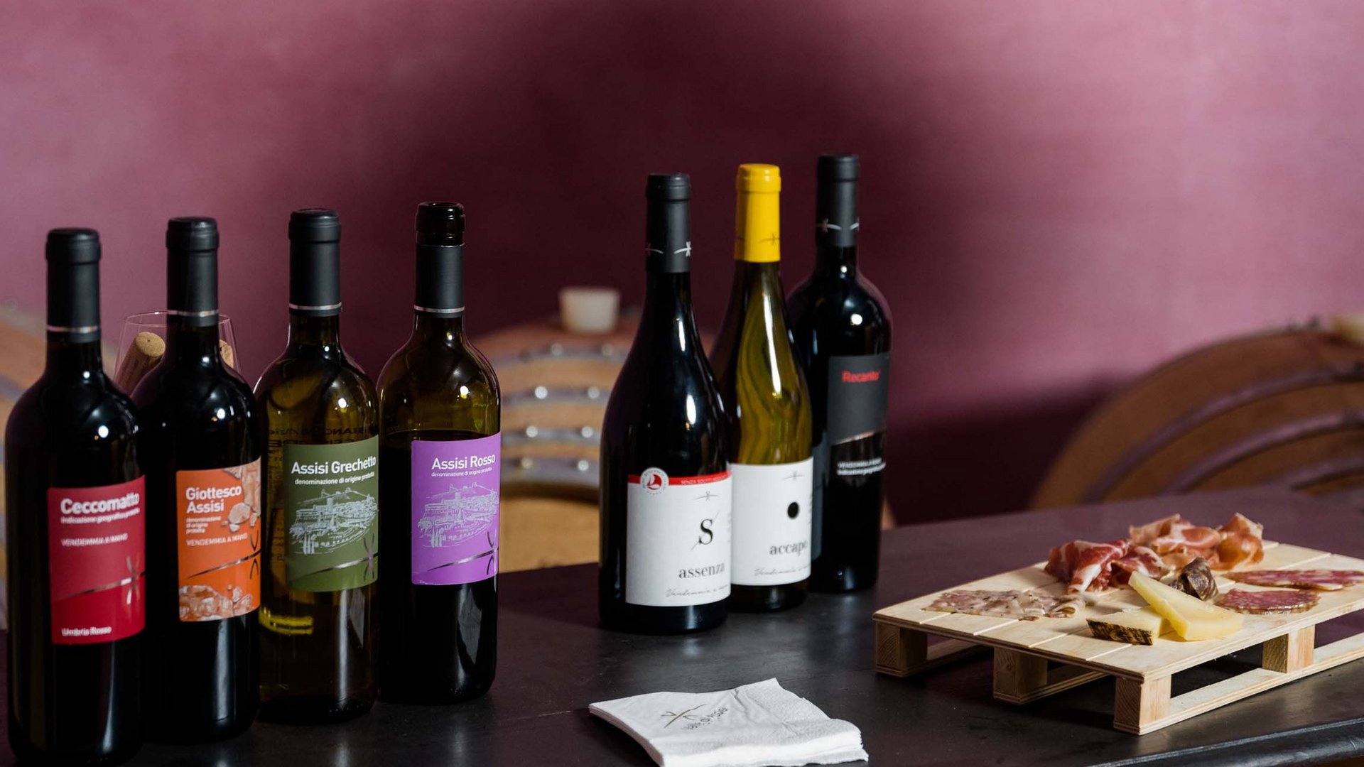 Pranzo di Pasquetta ad Assisi con Percorso SPA A Valle di Assisi, il Ristorante Recanto vi aspetta Set di bottiglie di vino e tagliere con salumi e formaggi su tavolo