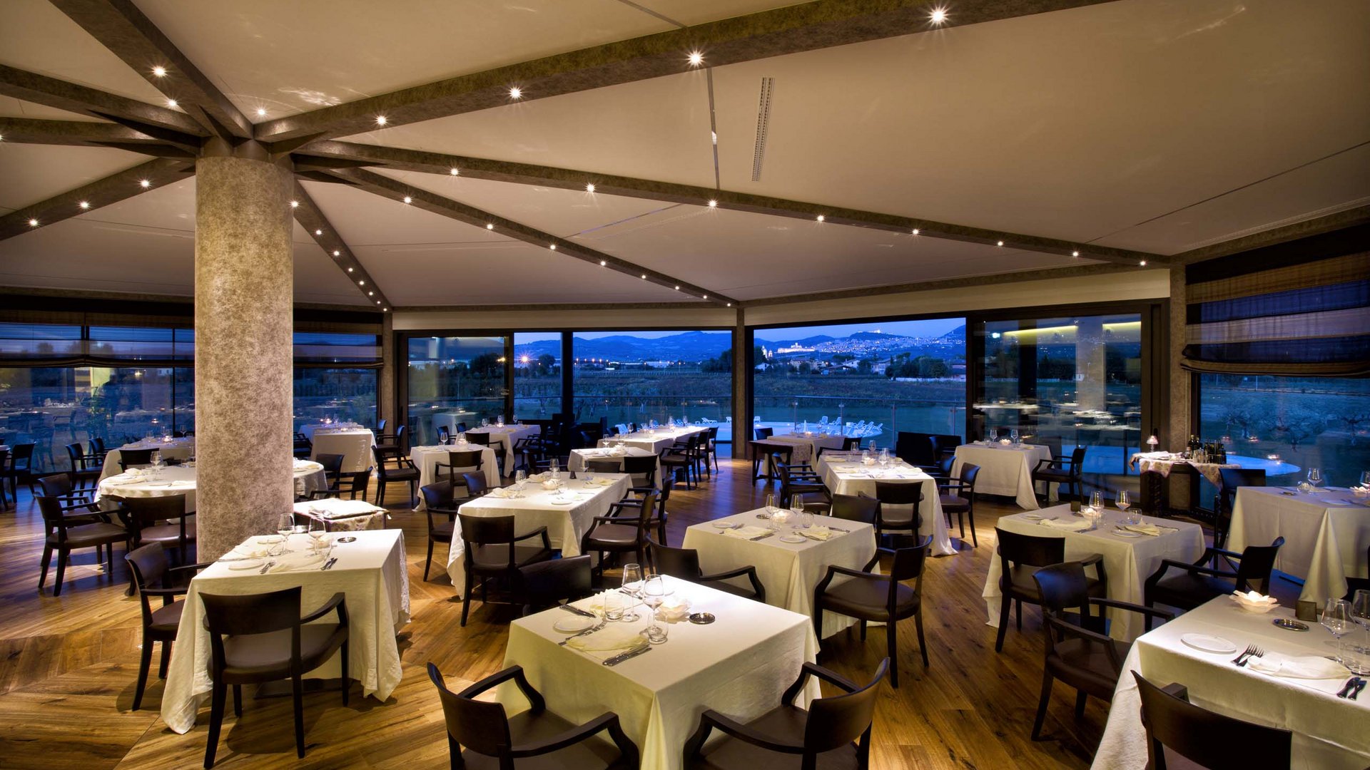 Hotel con ristorante vicino ad Assisi: benvenuti al Recanto Ristorante elegante con tavoli apparecchiati e vista panoramica serale.