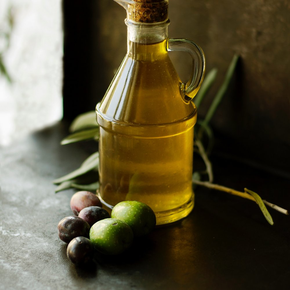 Hotel con ristorante vicino ad Assisi: benvenuti al Recanto Bottiglia di olio d'oliva con olive verdi e nere su sfondo scuro